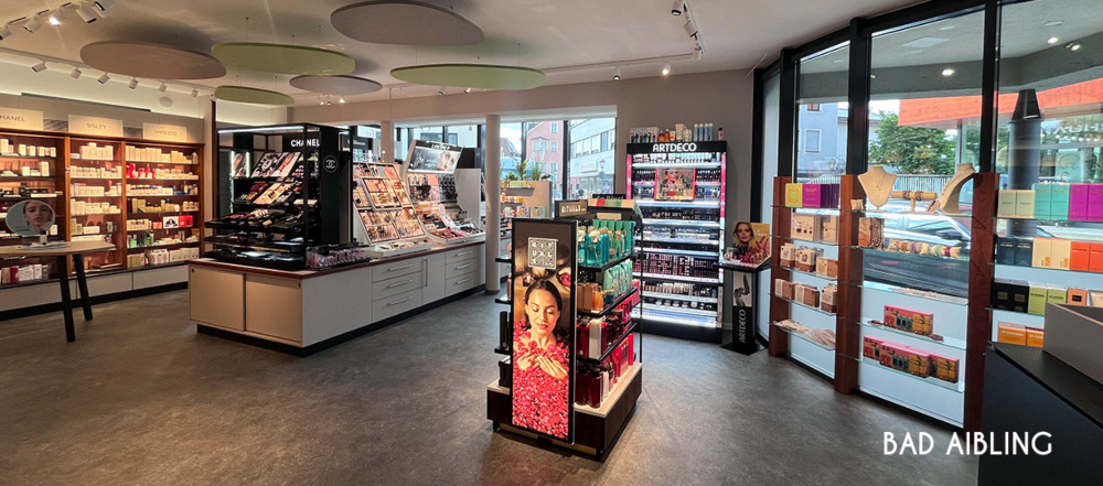Parfümerie Filiale Bad Aibling – Innenansicht mit Make-up-Theken für Chanel und Artdeco, digitalem Werbedisplay und großen Schaufenstern mit Blick auf die Straße.