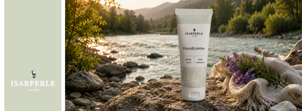 Isarperle Markenshop-Banner – Tube Isarperle Handcreme mit Duft Verbene (75ml) auf einem Stein an einem Gebirgsfluss im Abendlicht, daneben Lavendelzweige und ein Leinentuch. Links das Isarperle-Logo seit 1856 auf mintgrünem Hintergrund.