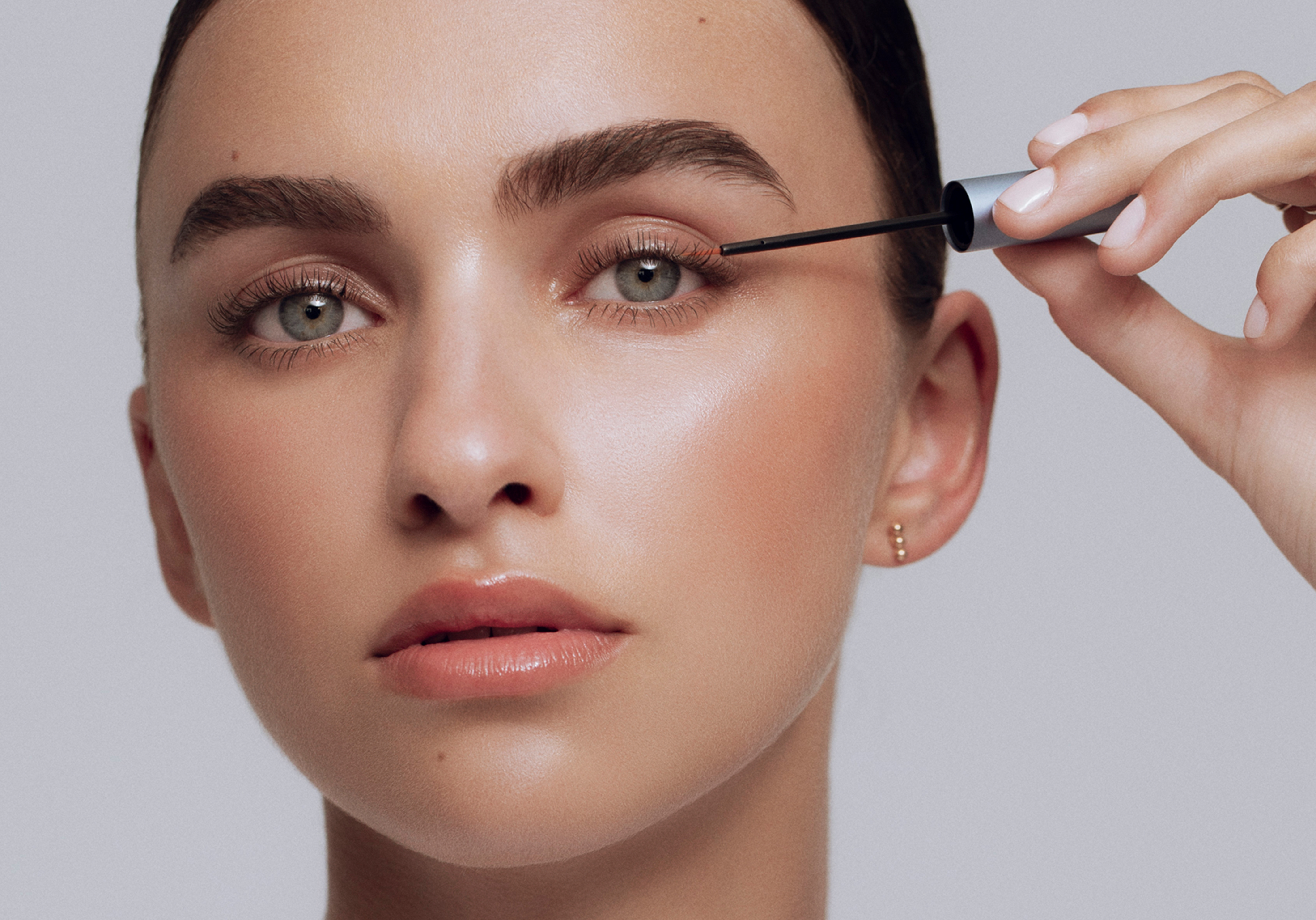 Nahaufnahme eines Gesichts mit natürlichem Make-up. Eine Person trägt mit einem feinen Applikator den RevitaLash Conditioner am oberen Wimpernkranz auf.