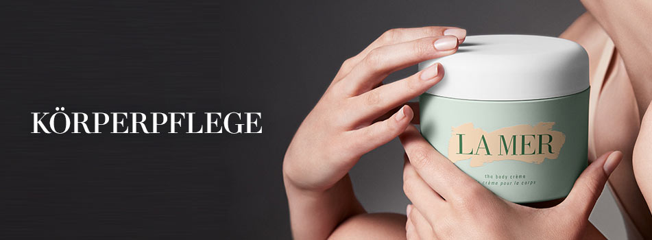 Werbebild für Körperpflege von La Mer. Eine Person hält einen großen, mintgrünen Tiegel mit weißem Deckel und goldfarbener Aufschrift: ‚La Mer – The Body Crème‘. Links im Bild steht der Schriftzug: ‚Körperpflege‘ in weißer Schrift auf dunklem Hintergrund.