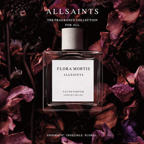 Parfumflakon „Flora Mortis“ von ALLSAINTS, umgeben von dunklen, violett-braunen Blüten. Darüber steht „ALLSAINTS – The Fragrance Collection for All“, darunter der Schriftzug „Enigmatic. Indelible. Floral.“