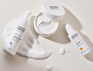 Körperpflegeprodukte von ANNEMARIE BÖRLIND, darunter Körpermilch, Creme und ein Pumpflakon, mit aufgeschäumtem Produkt dekorativ angeordnet.