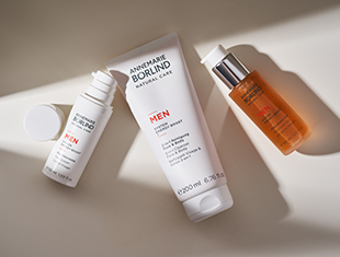 Pflegeprodukte für Männer von ANNEMARIE BÖRLIND, darunter Gesichtscreme, Augencreme und ein Pflegeöl, schlicht in Weiß und Orange gestaltet.