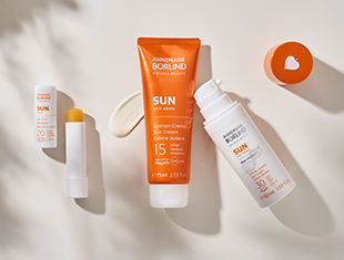 Sonnenschutzprodukte von ANNEMARIE BÖRLIND mit Lichtschutzfaktor 15, darunter Sonnencreme und Lippenpflege mit orangefarbenen Verpackungen.