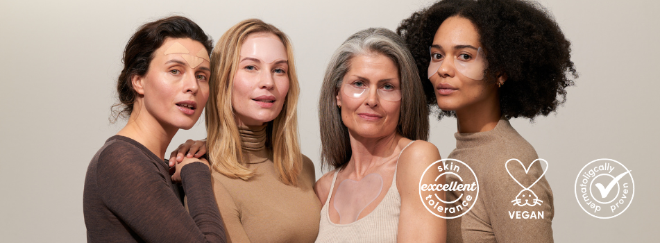 Vier Frauen unterschiedlichen Alters und Hauttyps mit durchsichtigen Pflegepatches im Gesicht. Sie stehen eng beieinander und schauen in die Kamera. Auf dem Bild sind Symbole für Hautverträglichkeit, Vegan und dermatologisch getestet eingeblendet.