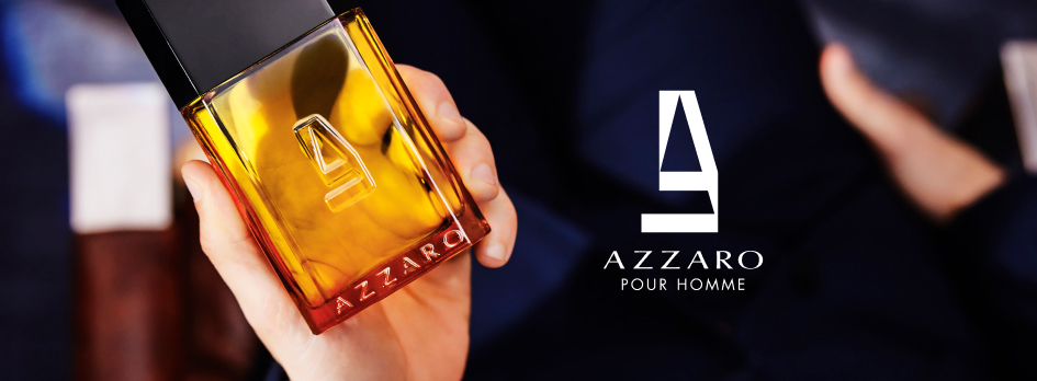 Nahaufnahme einer Hand, die eine Flasche Azzaro Pour Homme Parfum hält. Die Flasche ist rechteckig mit einem gold-orangefarbenen Glaskörper und schwarzem Verschluss. Rechts daneben das Azzaro-Logo mit dem Text 'Azzaro Pour Homme' vor einem dunklen Hintergrund.