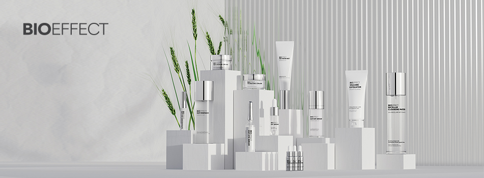 Pflegeprodukte von BIOEFFECT in eleganten weißen und silbernen Verpackungen, arrangiert auf weißen Podesten mit grünen Grashalmen im Hintergrund. Links oben das BIOEFFECT-Logo.