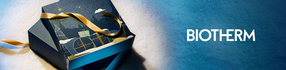 Stimmungsvoll beleuchtete Geschenkbox von Biotherm mit goldenem Band. Der Deckel ist mit winterlichem Motiv in Blau und Gold verziert. Die Box liegt auf schimmerndem Untergrund, rechts steht das Biotherm-Logo auf blau-weißem Farbverlauf.