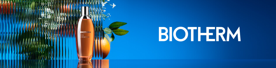 Werbung für Biotherm Eau d’Énergie. Eine orangefarbene Parfümflasche steht auf spiegelndem Untergrund vor einer geriffelten Glasfläche mit Orangen und weißen Blüten im Hintergrund. Rechts steht der Markenname 'Biotherm' auf einem blauen Farbverlauf.