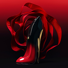 Parfümflakon in Form eines glänzend roten High Heels mit schwarzer Spitze, vor einem intensiven roten Hintergrund mit geschwungenem Satinband. Beschriftung darunter: 'Very Good Girl Elixir'.