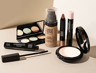 Dekorative Kosmetik für hypersensible Haut, dargestellt auf beigefarbenem Hintergrund. Gezeigt werden Make-up-Produkte wie Foundation, Puder, Concealer und Lidschatten – stilvoll und dermatologisch abgestimmt.