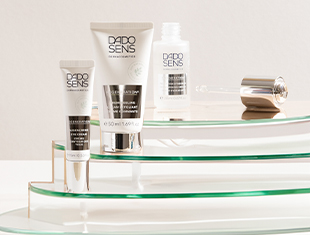 Produkte für regenerationsbedürftige Haut auf einem weißen Hintergrund mit grünem Unterton. Die Serie enthält Cremes, Öle und Ampullen in eleganten weißen Verpackungen.