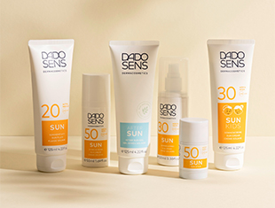 Sonnenschutzprodukte in weiß-gelben Tuben auf einem sandfarbenen Hintergrund. Entwickelt für sonnenempfindliche Haut, mit Lichtschutzfaktoren von 20 bis 50+.