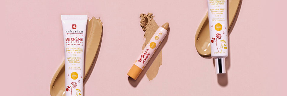 Drei BB-Produkte von Erborian auf rosa Hintergrund: BB Crème in Tube, BB Crayon in Stiftform und eine weitere BB Crème Tube, jeweils mit beiger Produkttextur daneben aufgetragen.