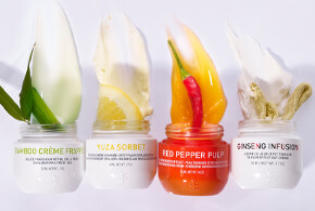 Vier Gesichtspflege-Cremes von Erborian in offenen Glastiegeln mit aufgetragenen Texturen und passenden natürlichen Zutaten: Bambus, Yuzu, rote Chili und Ginseng.