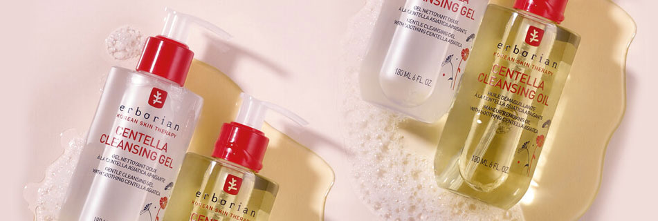 Erborian Centella Cleansing Gel und Cleansing Oil in transparenten Pumpflaschen mit rotem Verschluss, arrangiert auf einem pastellfarbenen Untergrund mit Schaum und Produkttexturen.