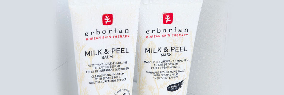 Zwei Tuben Erborian Milk & Peel Produkte: Balm und Mask, mit der Aufschrift zu Sesammilch und hauterneuernder Wirkung, vor hellgrauem, leicht beschlagenem Hintergrund.