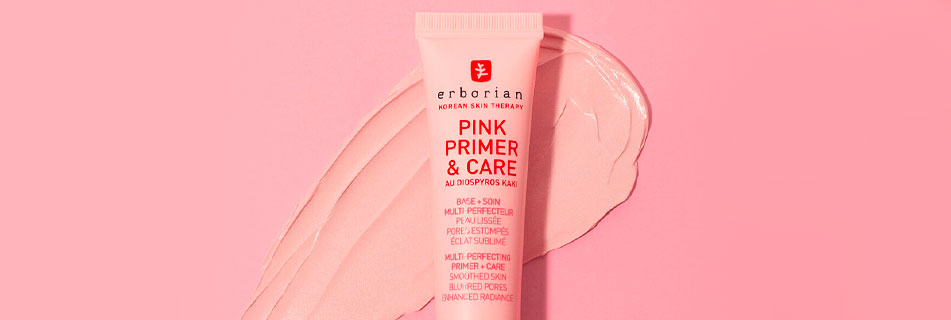 Erborian Pink Primer & Care in rosafarbener Tube, stehend auf einem pastellrosa Hintergrund mit aufgetragener Produkttextur im gleichen Farbton.