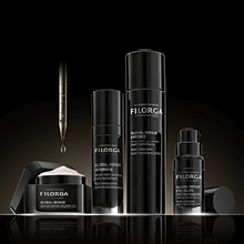 Vier Filorga Hautpflegeprodukte in eleganter schwarzer Verpackung vor dunklem Hintergrund. Abgebildet sind Creme, Serum, Lotion und Augenpflege aus der Global-Repair Linie, daneben eine Pipette mit einem Tropfen Serum.
