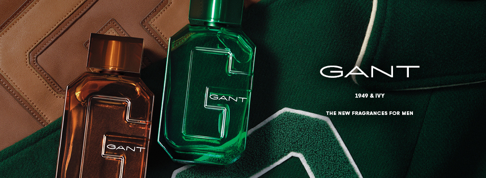 Zwei Herrenparfums von GANT, eines in einem bernsteinfarbenen und eines in einem grünen Flakon, liegen auf einer dunkelgrünen Stoffoberfläche neben einer braunen Lederstruktur. Rechts im Bild steht der Markenname GANT sowie der Hinweis „1949 & Ivy – The New Fragrances for Men“.