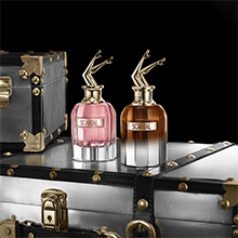 Zwei Jean Paul Gaultier Scandal Parfumflakons für Damen und Herren auf schwarzem Koffer, ikonisches Design mit goldenen Beinen als Verschluss.