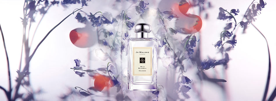 Flakon des Dufts „Wild Bluebell Cologne“ von Jo Malone London, umgeben von zarten blauen Glockenblumen und weichen Lichtreflexen in Pastelltönen.