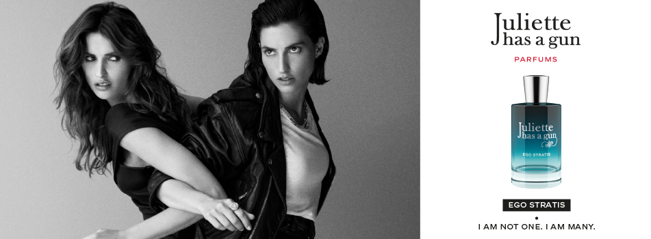 Werbebild für das Parfüm ‚Ego Stratis‘ von Juliette has a gun. Links sind zwei Frauen in Schwarz-Weiß gehalten abgebildet – eine zieht die andere entschlossen nach vorne. Rechts ist der türkis-blaue Flakon zu sehen. Text: ‚Juliette has a gun – Parfums – Ego Stratis – I am not one. I am many.‘