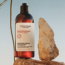 L'OCCITANE Haarpflegeprodukt mit botanischen Inhaltsstoffen vor Felsen und klarem Himmel.