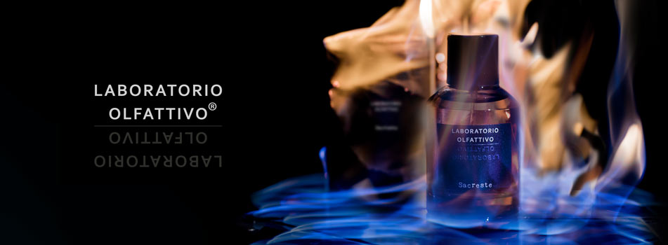Werbebild für das Parfüm ‚Sacreste‘ von Laboratorio Olfattivo. Eine dunkle Parfümflasche steht inmitten von blauen und orangefarbenen Flammen auf schwarzem Hintergrund. Links daneben der Markenname ‚Laboratorio Olfattivo‘ in weißer Schrift mit Spiegelung.