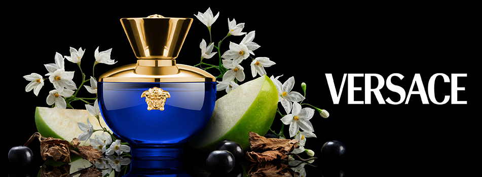 Werbebild eines Versace-Parfums in einem tiefblauen Flakon mit goldener Kappe und Medusa-Logo. Um den Flakon sind weiße Blüten, grüne Apfelscheiben, schwarze Beeren und getrocknete Blätter arrangiert. Rechts daneben steht in weißer Schrift das Markenlogo 'Versace' auf schwarzem Hintergrund.